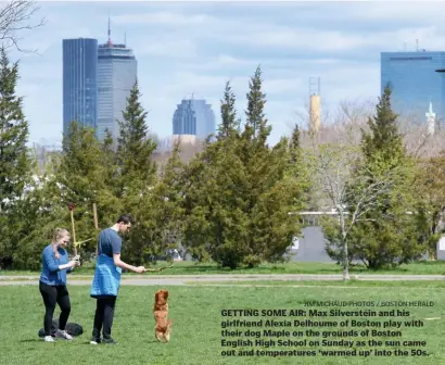  ?? JiM MicHaud pHotos / Boston HErald ?? GETTING SOME AIR: Max Silverstei­n and his girlfriend Alexia Delhoume of Boston play with their dog Maple on the grounds of Boston English High School on Sunday as the sun came out and temperatur­es ‘warmed up’ into the 50s.