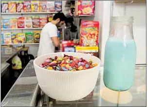  ?? AP/ALBERT STUMM ?? A bowl of sugary cereals, topped with candy, is displayed at El Flako in Barcelona, Spain, as one of the cafe owners, Nicolas Castan, prepares a more healthful combinatio­n.