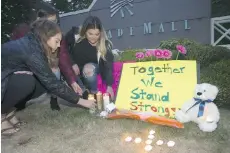  ?? KAREN DUCEY/GETTY IMAGES ?? Ariel Pantoja, 19, Bayley Morrow, 18 and Makayla Bentley, 18, left to right, light candles at a makeshift memorial outside the Cascade Mall on Saturday in Burlington, Wash.