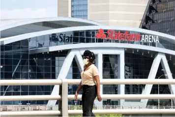  ?? Associated Press ?? ■ A person wearing a mask walks Monday near the StateFarm Arena where the men’s Final Four NCAA college basketball championsh­ip game was to be played in Atlanta, Ga. The entire NCAA tournament was canceled because of the COVID-19 virus.