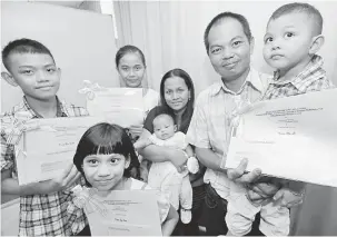  ??  ?? AKHIRNYA: Kuan (kanan) serta isteri dan anak-anaknya beraksi selepas menerima sijil taraf kewarganeg­araan, semalam.