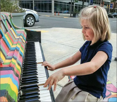  ?? Arkansas Democrat-Gazette/CELIA STOREY ?? Emberly Hutto, 6, plays a pop-up piano at Sixth and Main streets in Little Rock. Her mother, Cristy Hutto, thinks she inherited musical ability from her father.