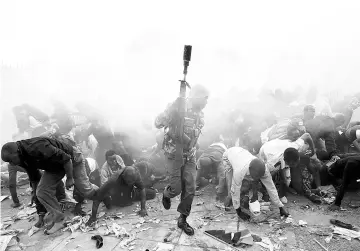  ??  ?? People fall as police fire tear gas to try control a crowd trying to force their way into a stadium to attend the inaugurati­on of Kenyatta at Kasarani Stadium in Nairobi. — Reuters photo