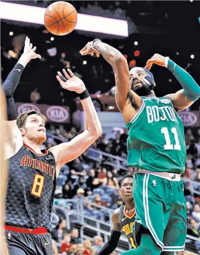  ?? ASSOCIATED PRESS ?? Boston Celtics' Kyrie Irving, right, passes the ball behind himself and over Atlanta Hawks' Luke Babbitt in the second quarter of an NBA basketball game in Atlanta.