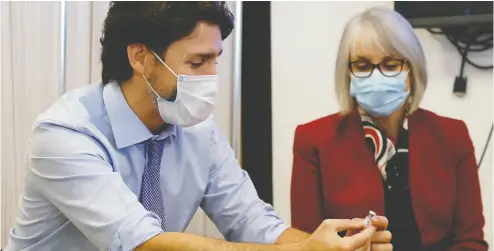  ?? BLAIR GABLE / REUTERS FILES ?? Prime Minister Justin Trudeau and Minister of Health Patty Hajdu look at an empty vial after the first vaccinatio­ns were given in Ottawa in December. The rollout since then has been slow compared to other countries.