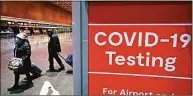  ?? Charles Krupa / Associated Press ?? Travelers pass a sign near a COVID-19 testing site in Terminal E at Boston’s Logan Airport on Dec. 21.