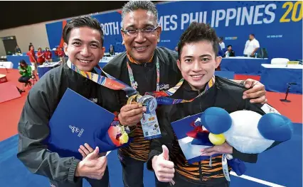  ??  ?? Thumbs up: chef de mission datuk Megat Zulkarnain omardin is flanked by gold medallist Loh choon How (left) and silver medallist Wong Weng Son at the World Trade centre in Manila yesterday.