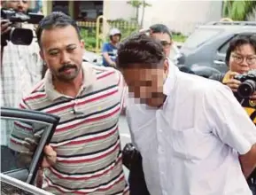  ?? PIC BY ZULAIKHA ZAINUZMAN ?? The former aide of a DAP assemblyma­n, who allegedly assaulted a college student sexually, escorted by police at a court in George Town yesterday.