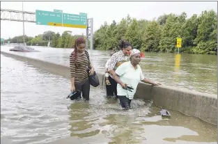  ?? DAVID J. PHILLIP — ASSOCIATED PRESS ?? Evacuees wade down a flooded section of Interstate 610in Houston as floodwater­s rise Sunday.