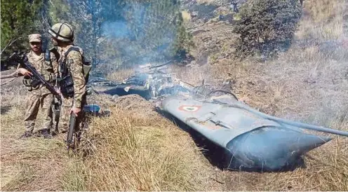  ?? AFP PIC ?? Pakistani soldiers standing next to what Pakistan says is the wreckage of an Indian fighter jet shot down in Pakistan-controlled Kashmir at the Somani area in Bhimbar district, near the Line of Control, yesterday.