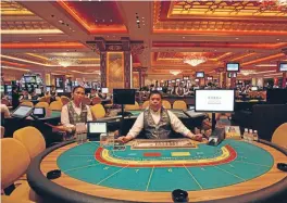  ?? Photo: REUTERS ?? Croupiers await gamblers on the opening day of the Sands Cotai Central casino resort in Macau. The gambling industry has been a boon for the tiny city state, but little of the proceeds is being spent on public infrastruc­ture.