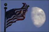  ?? CHARLIE RIEDEL—ASSOCIATED PRESS ?? In this June 29, 2020, file photo, a flag flies in the wind above City Hall as the waxing gibbous moon passes behind clouds overhead in Kansas City, Mo.