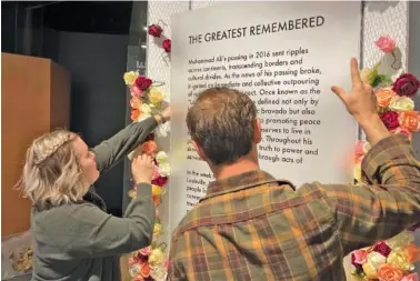  ?? AP PHOTOS/BRUCE SCHREINER ?? Above: Bess Goldy, left, curator of a new exhibit at the Muhammad Ali Center, helps arrange a display Thursday in Louisville, Ky. Below: Goldy holds a display recounting the days after Ali’s death in 2016.