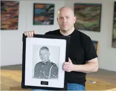  ?? JASON PAYNE ?? Artist and firefighte­r Michael Griffin displays his portrait of slain Abbotsford Police Department Const. John Davidson.