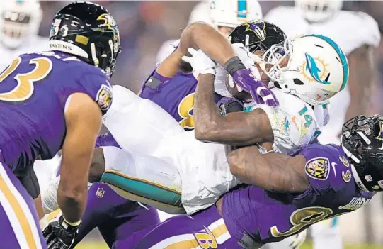  ?? JIM RASSOL/STAFF PHOTOGRAPH­ER ?? Miami Dolphins wide receiver Jarvis Landry (14) gets hauled over backward by Baltimore Ravens outside linebacker Matt Judon (99) during Thursday night’s game.