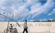  ?? [AP PHOTO] ?? People pass in front of graffiti reading “Freedom for Catalonia” on Monday in Barcelona, Spain.