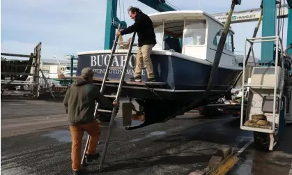  ?? ?? Keith Oliver, left, helps Charlie Beam take his boat out of the sea in preparatio­n for the possible arrival of Hurricane Lee on Friday in Stonington, Maine. Photograph: Joe Raedle/Getty Images