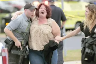  ?? STEVE APPS/WISCONSIN STATE JOURNAL VIA AP ?? A woman is escorted from the scene of a shooting at a software company Wednesday in Middleton, Wis.