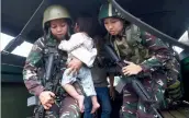  ?? — AFP ?? Philippine Army troopers escort a rescued child in Marawi, Philippine­s.
Civilians held hostage by Islamist militants occupying Marawi have been forced by their captors to loot homes
The civilians were forced by militants to serve as sex slaves, the...