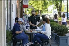  ?? GERRY BROOME — THE ASSOCIATED PRESS ?? Patrons are assisted while dining on a sidewalk along Franklin Street in Chapel Hill, N.C. As consumers increasing­ly venture away from home, demand has begun to shift away from manufactur­ed goods and toward services, from airline fares to restaurant meals, triggering inflation in those areas.