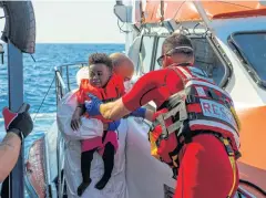  ?? AP ?? Maltese armed forces personnel help a child board their ship from the German humanitari­an vessel ‘Alan Kurdi’ on Sunday.