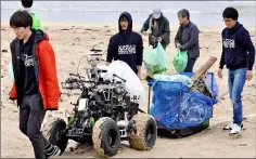  ??  ?? A robot vehicle carrying collected garbage follows students around during a test cruise on a beach in Japan. — Japan News-Yomiuri photo