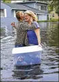  ?? DEDE SMITH / THE FLORIDA TIMES-UNION VIA AP ?? Charlotte Glaze gives Donna Lamb a teary hug as she floats out some of her belongings in Jacksonvil­le, Fla., Monday.