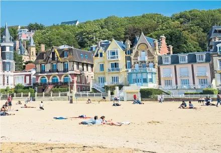  ??  ?? ● Sun worshipper­s relax on the beach in Trouville, north-west France