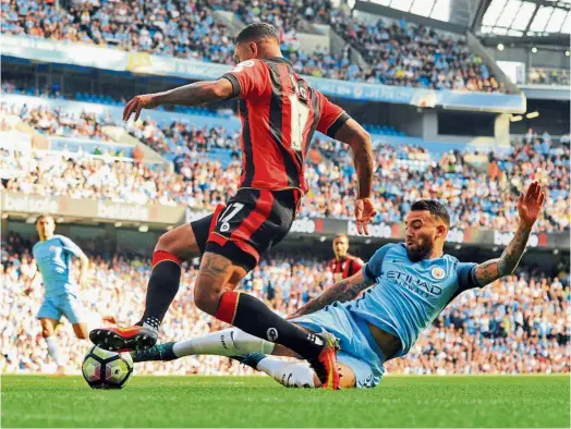  ??  ?? Move aside: Manchester City’s Nicolas Otamendi (right) vying for the ball with Bournemout­h’s Joshua King during their English Premier League match at the Etihad yesterday. — AP