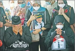  ?? (AP/Trisnadi) ?? Relatives weep as they pray during the burial of Fadly Satrianto, a victim of the crash of Sriwijaya Air flight SJ-182 in Surabaya, East Java, Indonesia, on Jan. 15. More searchers and rescuers joined the search for wreckage and victims from the Indonesian plane that crashed in the Java Sea.