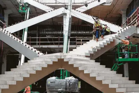  ?? Brett Coomer / Staff photograph­er ?? Workers last week continue installing one of the staircases at POST Houston, the redevelopm­ent of the former Barbara Jordan Post office downtown. The basic structure and mechanical systems are on track to be done this year.