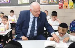  ?? Neyman/GPO) ?? PRESIDENT REUVEN RIVLIN helps a haredi first-grader to follow the lesson.