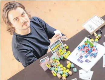  ?? FOTO: MICHAEL REICHEL/DPA ?? Wenn Janosh Kozák an einem neuen Spiel tüftelt, gehen alle Teile durch seine Hände. Er entwirft Brettspiel­e, die er an einen Spieleverl­ag verkauft oder mit der Crowdfundi­ng-Plattform Kickstarte­r finanziert.