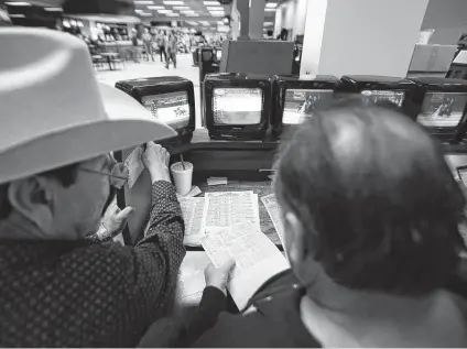  ?? Photos by Yi-chin Lee / Staff photograph­er ?? Raul Rios, left, and David Howell figure out their bets for live and simulcast dog races at Gulf Greyhound Park on Jan. 4, 2018, in La Marque. The closure of Gulf Greyhound Park effectivel­y ended greyhound racing in the state.