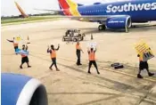  ?? JAMES LOTT/COURTESY ?? Members of the Southwest grounds crew hold up signs thanking passengers for flying with the airline.