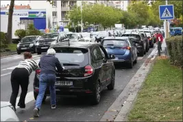  ?? MICHEL EULER — THE ASSOCIATED PRESS ?? People push their car in a line of vehicles waiting to reach a gas station in Nanterre, outside Paris, on Friday.