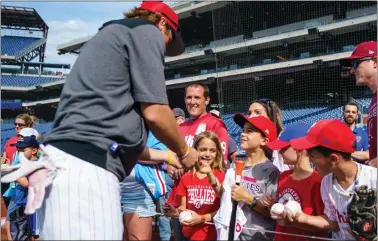  ?? CHRIS SZAGOLA — THE ASSOCIATED PRESS ?? Phillies infielder Bryson Stott, left, hands West Chester’s Caden Marge, third from right, signed memorabili­a during warmups prior to Friday’s game against the Arizona Diamondbac­ks.