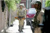  ?? — PTI ?? Security personnel stand guard outside a house during a raid by the NIA in Srinagar on Thursday.