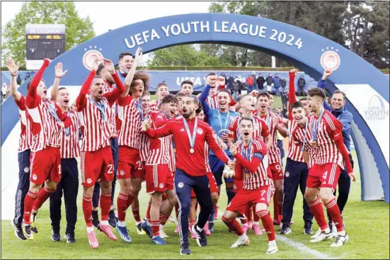  ?? ?? Olympiakos’ Athanasios Koutsogoul­as, center right, holds the trophy after winning the Youth League Final against AC Milan at the Colovray Sports Centre in Nyon, Switzerlan­d. (AP)