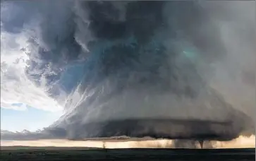  ?? Photog raphs by Kelly DeLay ?? SISTER TORNADOES form beneath a massive supercell in Simla, Colo., on June 4. Storm chaser Kelly DeLay endured hail and rain to capture the rare phenomenon, calling it a “once-in-a-lifetime image.”