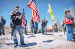  ?? EDDIE MOORE/JOURNAL ?? Derek Garcia of Albuquerqu­e carries a U.S. flag and an AR-15 while attending a rally for protecting gun rights outside the Roundhouse in Santa Fe in April. Around 130 people, many with guns, attended the rally.