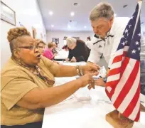  ?? STAFF PHOTO BY DAN HENRY ?? Mary Russell, left, assists residents with their applicatio­ns to vote Tuesday at the Hixson Fellowship Hall in Red Bank Cumberland Presbyteri­an Church. Russell has been helping with elections for the past 32 years.