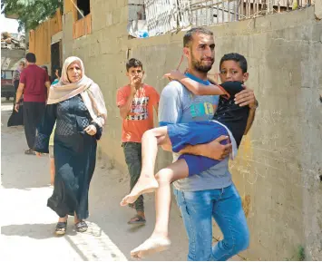  ?? SAID KHATIB/GETTY-AFP ?? A Palestinia­n man carries an injured boy following an Israeli airstrike Saturday in the Gaza Strip, during the territory’s worst escalation of violence since last year.