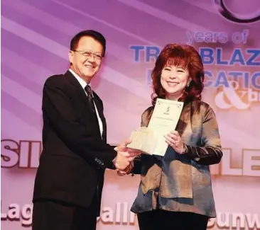  ??  ?? Deserving: Cheah (left) presenting a long-service award to Lee at a recent silver jubilee gala dinner.