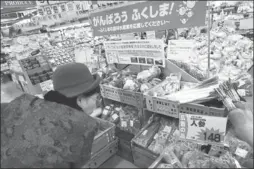  ??  ?? A shopper inspects the food radiation assessment method and its result for vegetables sold at a store in Fukushima, Japan.