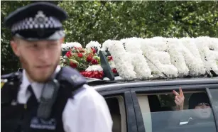  ??  ?? Hostile: One of the mourners raises two fingers out of the car window