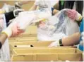  ??  ?? Volunteers sort meats at the food bank.