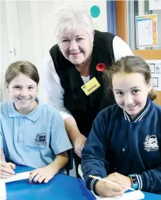  ??  ?? Longwarry and District History Group member Paula Rupe works on the crosses with Longwarry Primary Schoolo students Bonnie Carkeek and Tianna Kenworthy.