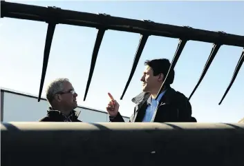  ?? MARK TAYLOR ?? Prime Minister Justin Trudeau chats with Rod Lewis in front of a combine at his Lewis Land Limited farm near Gray on Thursday. The PM was on the hot seat defending his carbon tax during his stop in the province.