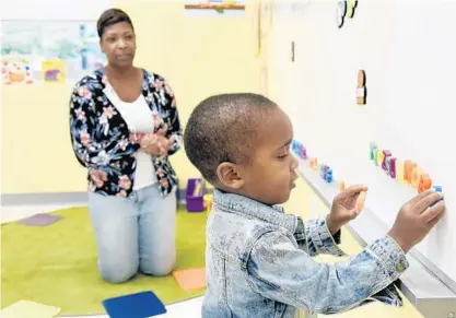  ?? KIM HAIRSTON/BALTIMORE SUN PHOTOS ?? Imani Sims, teacher's aide, watches as Seven Neverdon, 2, places letters on the whiteboard as he visits the Loyola Early Learning Center, which opened Sept. 12. The year-round preschool is the third Jesuit school in the city opened by the Rev. William...